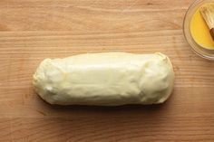 a loaf of bread sitting on top of a wooden table next to a bowl of butter