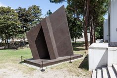 a sculpture in the middle of a park with stairs leading up to it's entrance