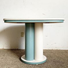 a white and blue table sitting on top of a carpeted floor next to a wall