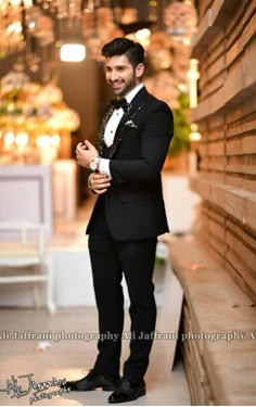 a man in a tuxedo standing next to a wall