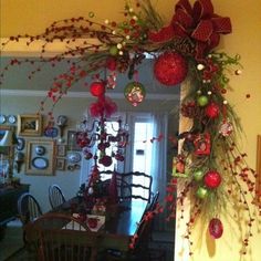 the christmas decorations are hanging on the wall in the dining room, while the table is decorated with red and green ornaments