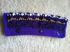 a purple and yellow knitted headband laying on top of a white carpeted floor