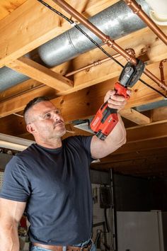 a man is holding a drill in his hand and working on the ceiling above him