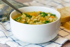 a white bowl filled with soup next to some bread