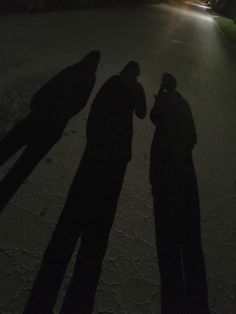 two people standing next to each other in the dark with their shadows on the ground