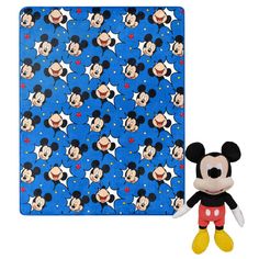 a mickey mouse plush toy next to a blue and white blanket with stars on it