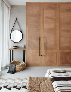 a bedroom with a bed, mirror and wooden cupboards