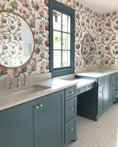 a bathroom with floral wallpaper and two sinks in front of a large mirror on the wall