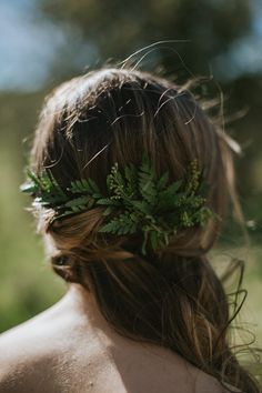 the back of a woman's head wearing a green leafy hair piece on her head