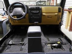 the interior of a vehicle with its door open and steering wheel in place on the floor