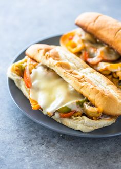 two sandwiches on a plate with melted cheese and peppers in the middle, sitting next to each other