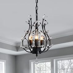 a chandelier hanging from the ceiling in a living room with windows and white walls