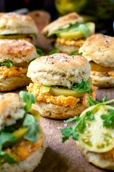 small sandwiches with cheese, lettuce and other toppings on a wooden board