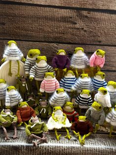 a group of knitted frog figurines sitting on top of a wooden table