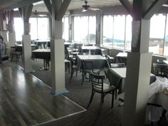 an empty restaurant with tables and chairs in front of large windows that look out onto the water