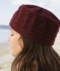 a woman wearing a red knitted hat on the beach