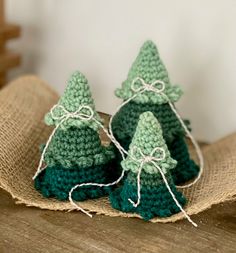 three small crocheted christmas trees sitting on top of burlock