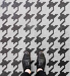 a person standing in front of a black and white tiled floor with their feet on the ground