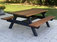 a wooden picnic table sitting on top of a white tile floor next to a potted plant