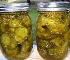 four jars filled with pickles sitting on top of a table