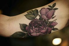 a close up of a person's arm with a flower tattoo on the arm