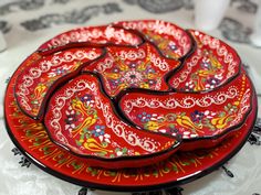 a red plate with designs on it sitting on a table