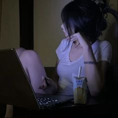 a woman sitting in front of a laptop computer on top of a desk next to a drink