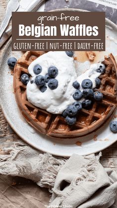 a plate topped with waffles covered in blueberries and whipped cream next to a fork