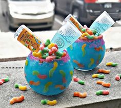 two bowls filled with candy sitting on top of a cement slab next to a street