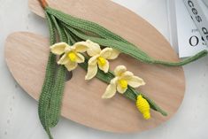 crocheted yellow flowers are on a wooden cutting board