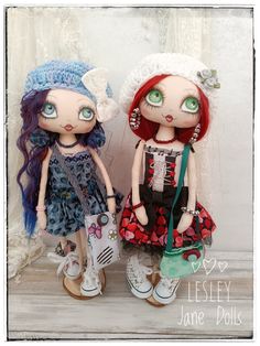 two dolls standing next to each other in front of a white wall with lace on it