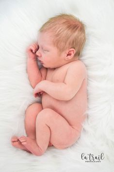 a baby is laying down on a fluffy white blanket and holding his hand up to his ear