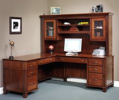 a wooden desk with a computer on top of it in front of a brown wall