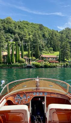 a boat is on the water in front of some trees and houses with lots of greenery