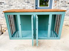 a blue cabinet sitting on top of a cement floor next to a door and window