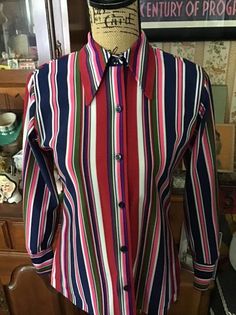 "Vintage 1970's Polyester, long sleeve blouse. Great multi-color stripes. Colors are brighter in person than show up in pictures. Buttons down the front. The label is *KOLORTRON* By Koret Of California. *SCROLL DOWN FOR MORE INFORMATION* **I DO COMBINE SHIPPING** CONDITION: One small Gold spot on the lower, front below the buttonhole near the hemline (SEE PIX). MEASURES: Bust~36\" Waist~32\" Hips~40\" Sleeve length~21 1/2\" Shoulder seam to shoulder seam~14 1/2\" Back of collar to bottom~25\" *W Multicolor Long Sleeve Top With Vertical Stripes, Multicolor Long Sleeve Vintage Blouse, Vintage Striped Shirt For Fall, Vintage Striped Collared Blouse, Vintage Striped Button-up Blouse, Multicolor Button-up Top With Striped Collar, Retro Long Sleeve Top With Striped Collar, Vintage Striped Fitted Blouse, Fitted Striped Vintage Blouse