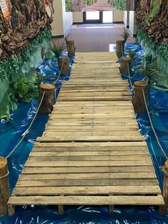 a wooden bridge is in the middle of a blue water covered walkway that leads to an entrance