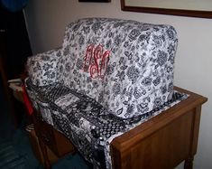 a couch covered in black and white fabric with red monogrammed initials on it