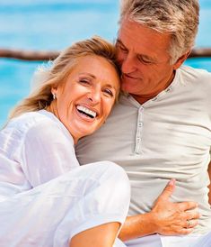 a man and woman sitting next to each other with their arms around each other smiling