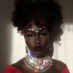 a woman in a red dress wearing a necklace and choker with lights on her face