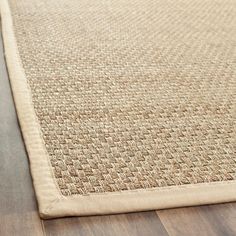 a close up view of a beige rug on the floor with wood floors and hard wood flooring