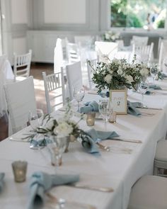 the table is set up with white and blue linens, silverware, and flowers