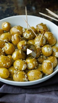 a white bowl filled with olives covered in cheese and topped with toothpicks