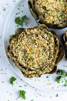 three artichokes on a plate with parsley sprinkled in them