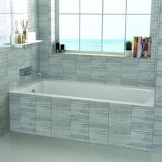 a bath tub sitting in front of a window next to a shelf with books on it