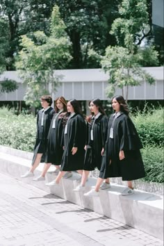 a group of women in graduation gowns are walking down the street with their backs turned