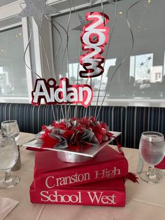 a stack of books sitting on top of a table next to wine glasses and silverware