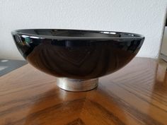 a black bowl sitting on top of a wooden table