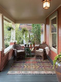 a porch with two wicker chairs and a rug on the floor