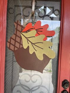 a red door with a fall leaf and acorn on it's glass window